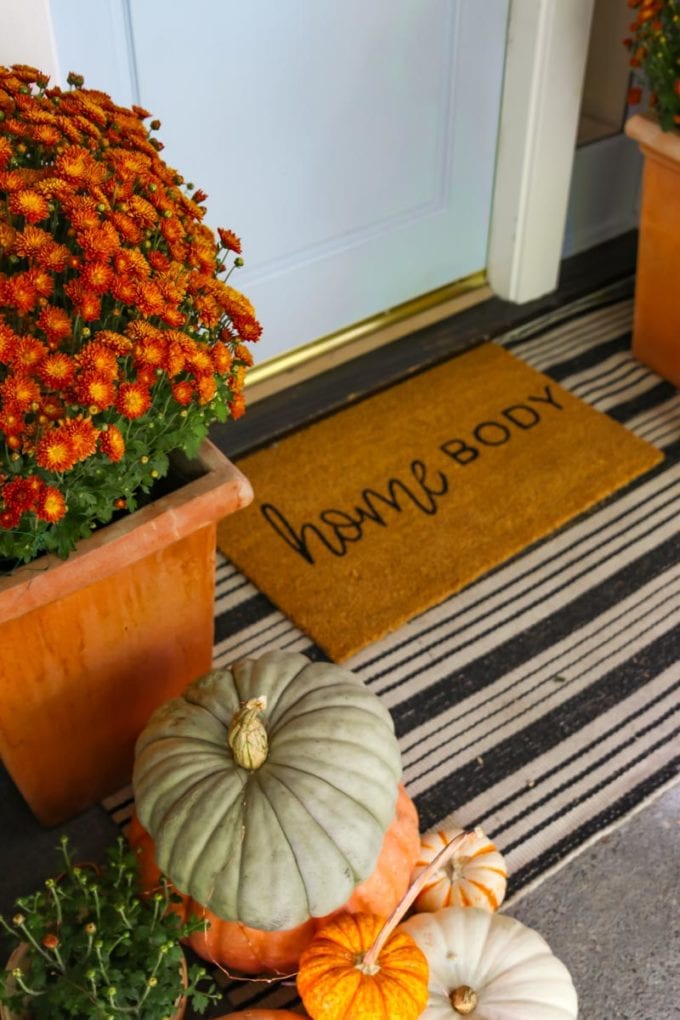 fall front doormat layered with pumpkins